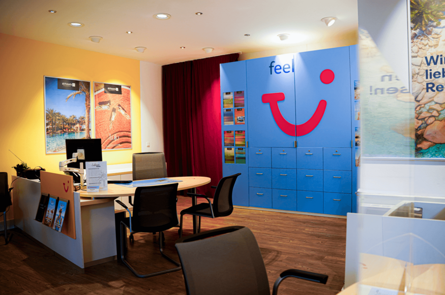 Beratungsplatz im Reisebüro mit TUI-Logo und bunter Wandgestaltung.